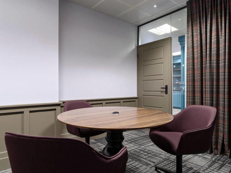 Refurbished meeting room with dark purple chairs, brown panelling and central table